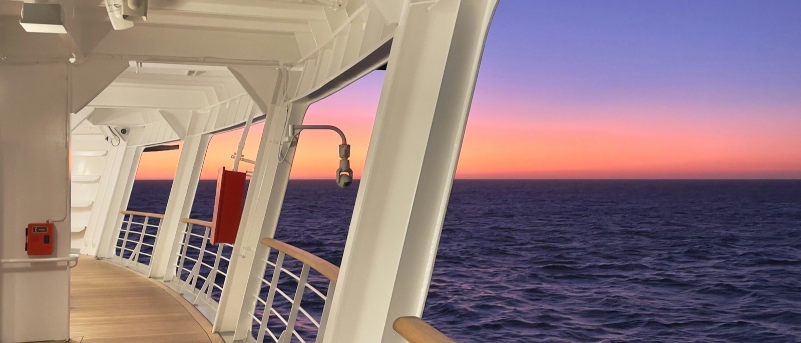 Passeio externo de navio de cruzeiro ao entardecer, com o mar aberto ao lado